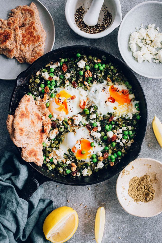 Green Shakshuka with spinach, green peas and spices, topped with creamy goat cheese and walnuts